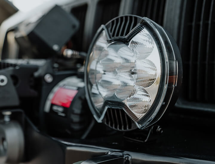 Close-up of a bumper-mounted SlimLite 6” LED light with an SAE driving shield for street-legal visibility and off-road use.