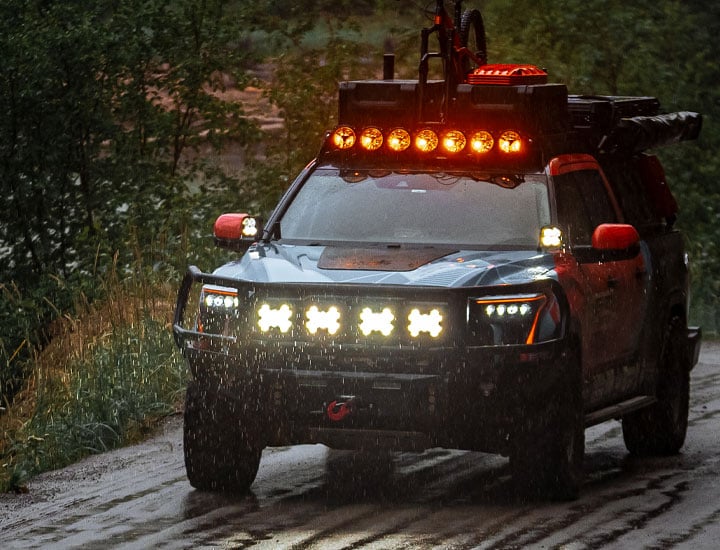 Side view of two SlimLite 8” Lights (SKU 0108) installed on the bumper of a vintage Toyota Land Crusier, on and uncovered.